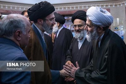 L: R: Son of Iran’s Supreme Leader Mojtaba Khamenei shaking hands with Hossein Taeb
